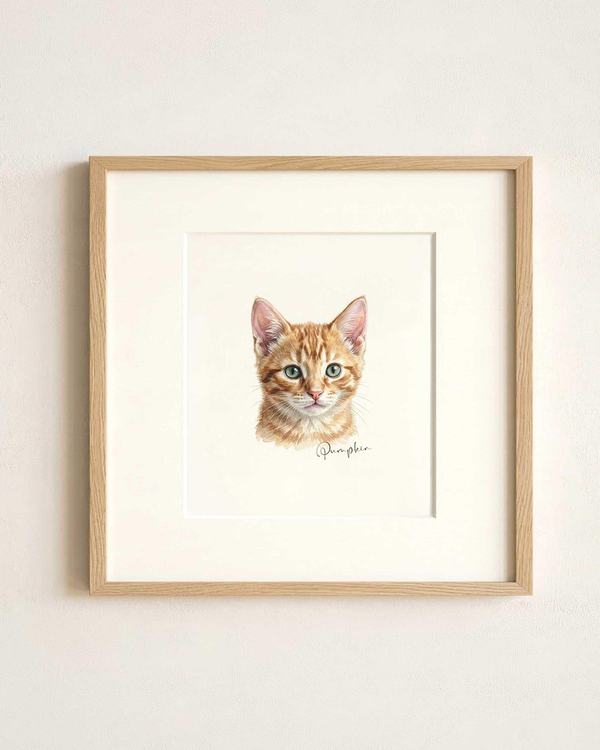 May include: A framed watercolor print of a ginger tabby kitten. The artwork features the kitten's head and shoulders, with detailed fur and green eyes. The print is set in a white mat and a light wood frame, with the name "Pumpkin" written in script.