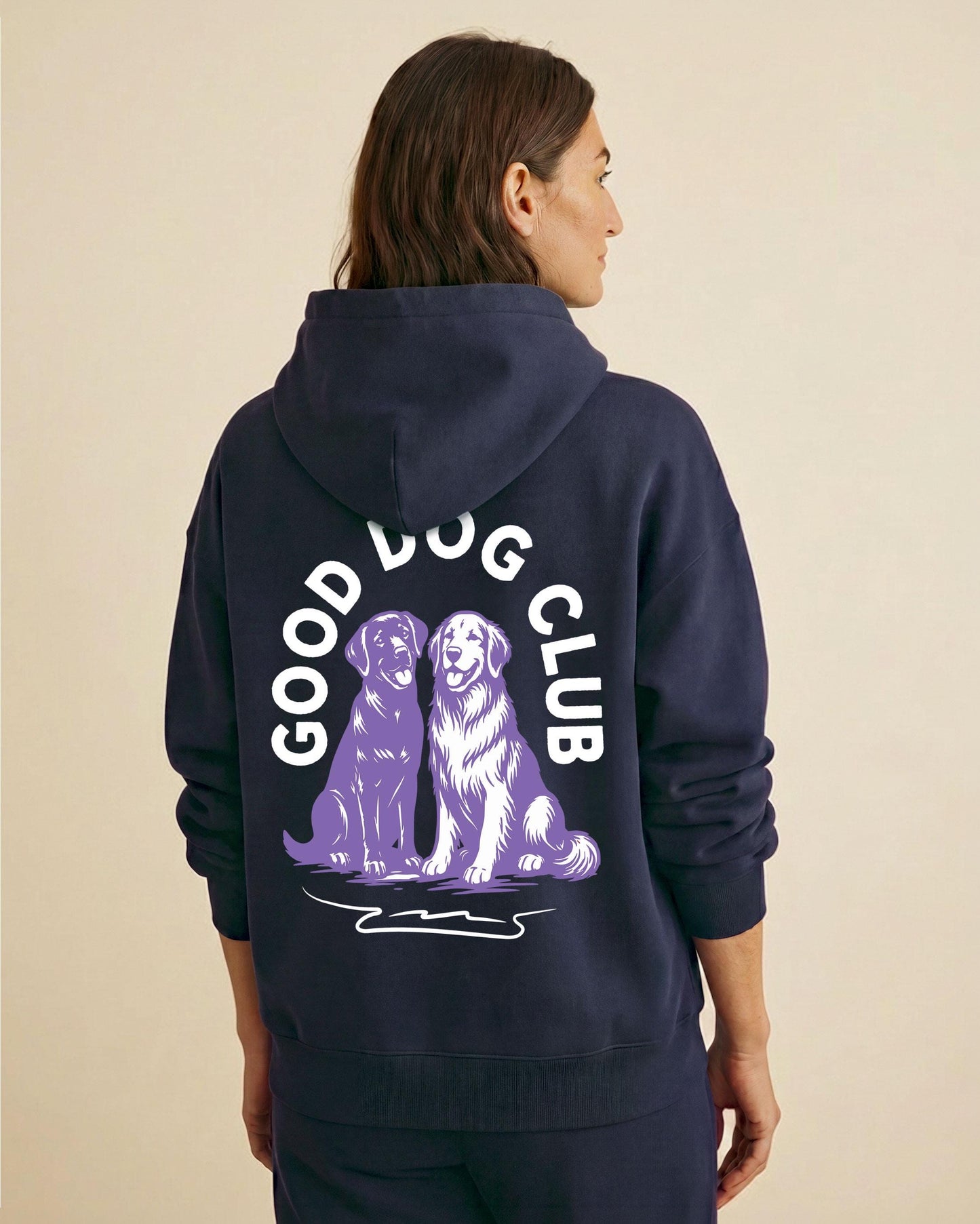 Woman wearing a navy dog mom hoodie from behind, featuring a Good Dog Club graphic with two purple golden retrievers and bold white arched lettering.