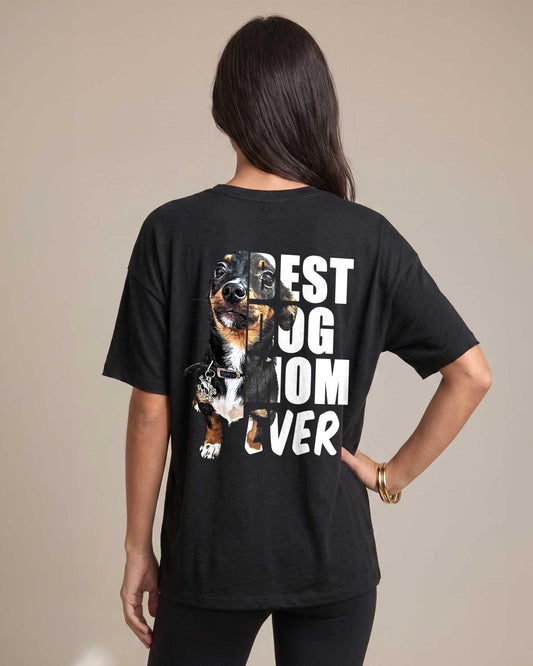 Woman wearing black oversized tee showing the back graphic of a dachshund photo integrated into bold white text reading Best Dog Mom Ever
